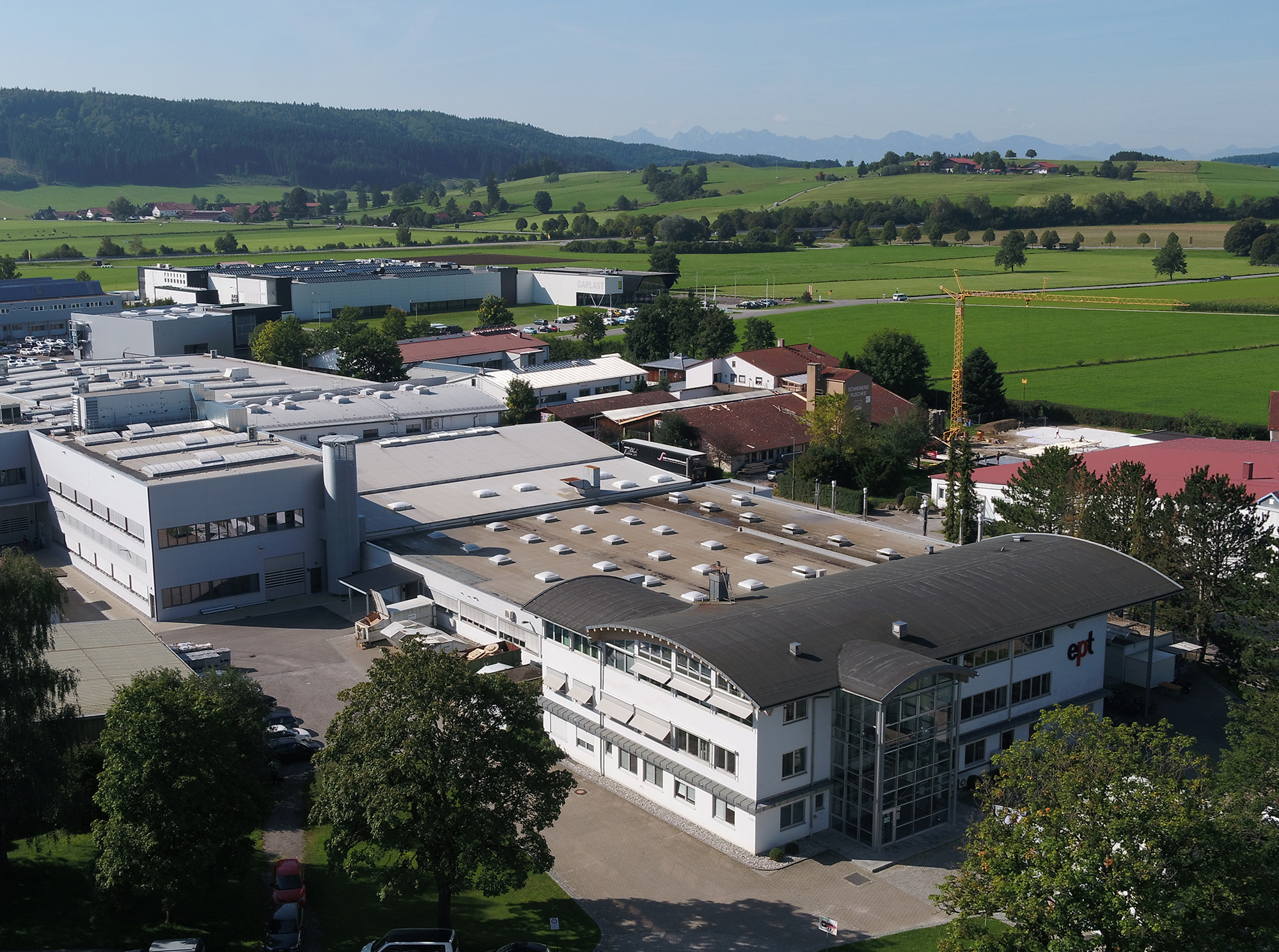Auf dem Bild ist eine Industrieanlage mit mehreren Gebäuden, direkt umgeben von einer grünen Landschaft, zu sehen.